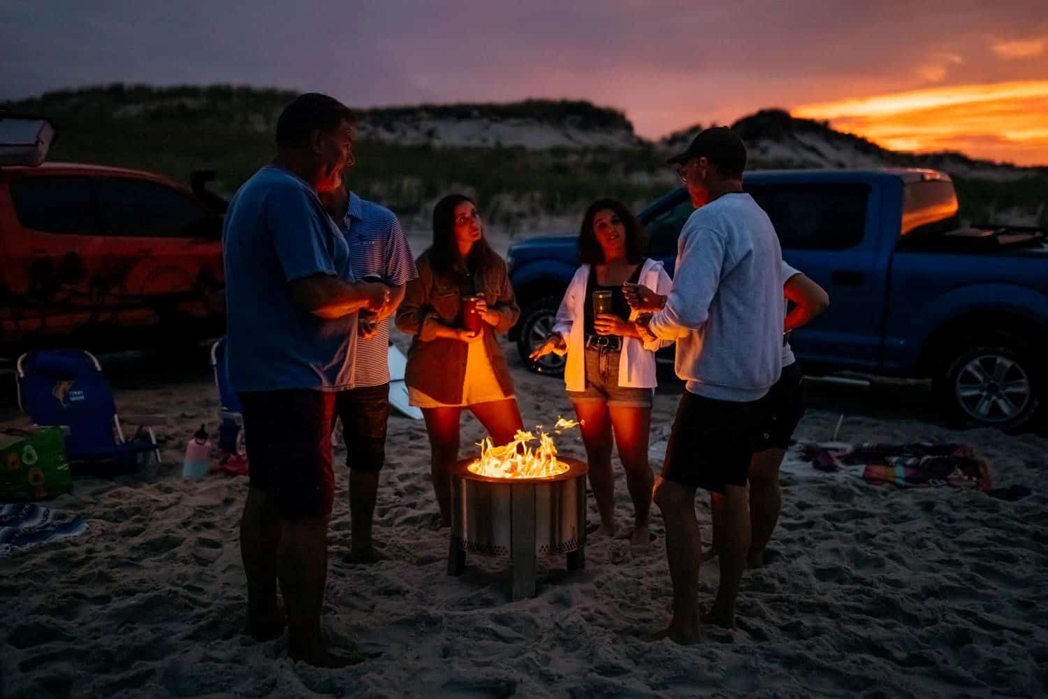 A photo of a group of friends on the beach around the Y Series Firepit