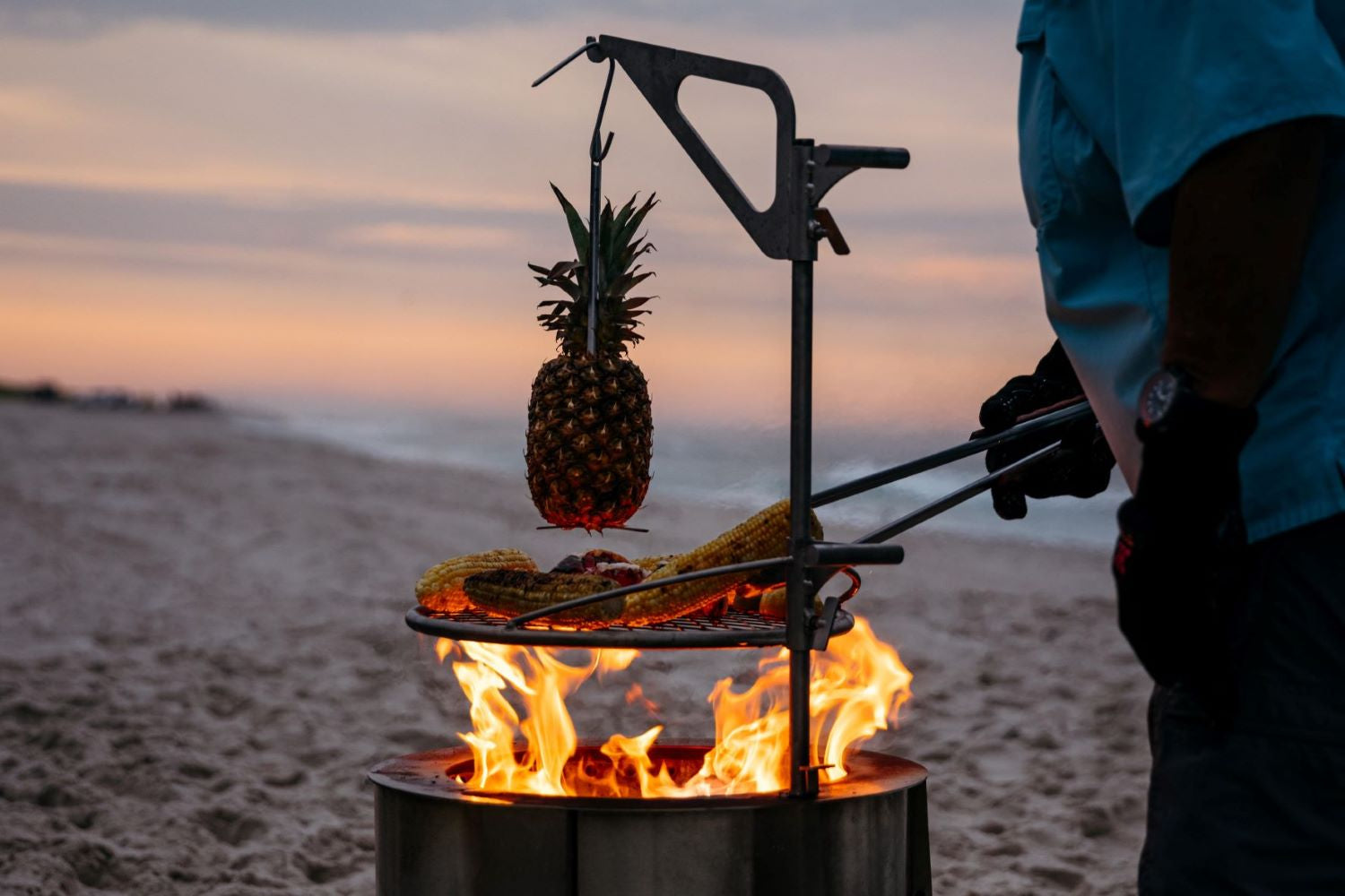 This is a photo of a man grilling corn on the Outpost over the Y Series Firepit